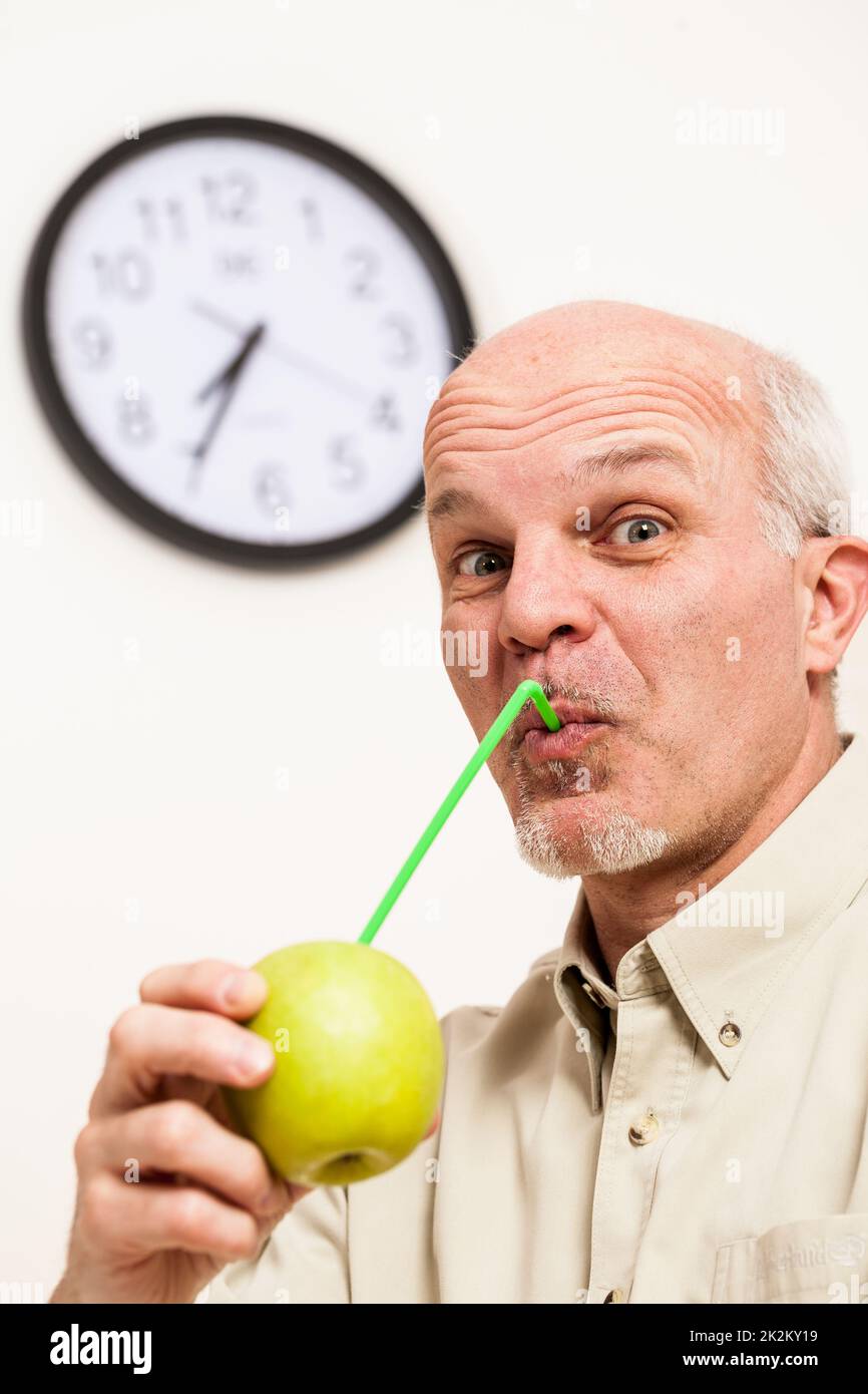 Bearded mature man sipping juice from apple Stock Photo