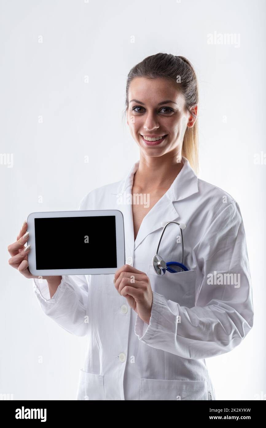Smiling friendly doctor holding up a blank tablet pc Stock Photo