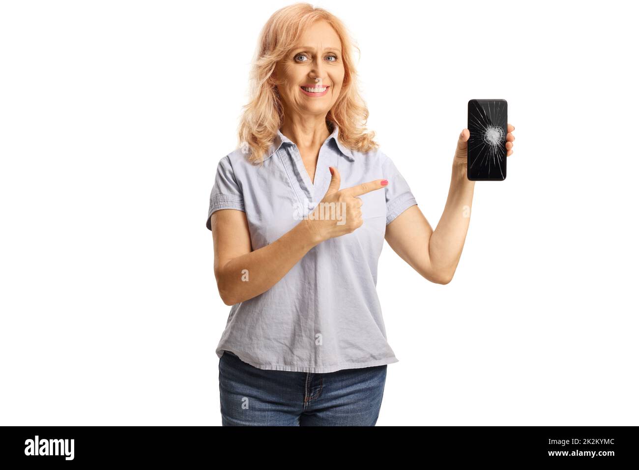 Casual mature woman holding a smartphone and pointing at the broken screen isolated on white background Stock Photo