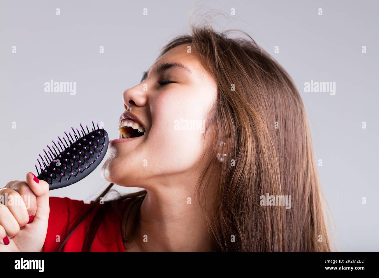 passionate girl pretending to sing with her hairbrush Stock Photo