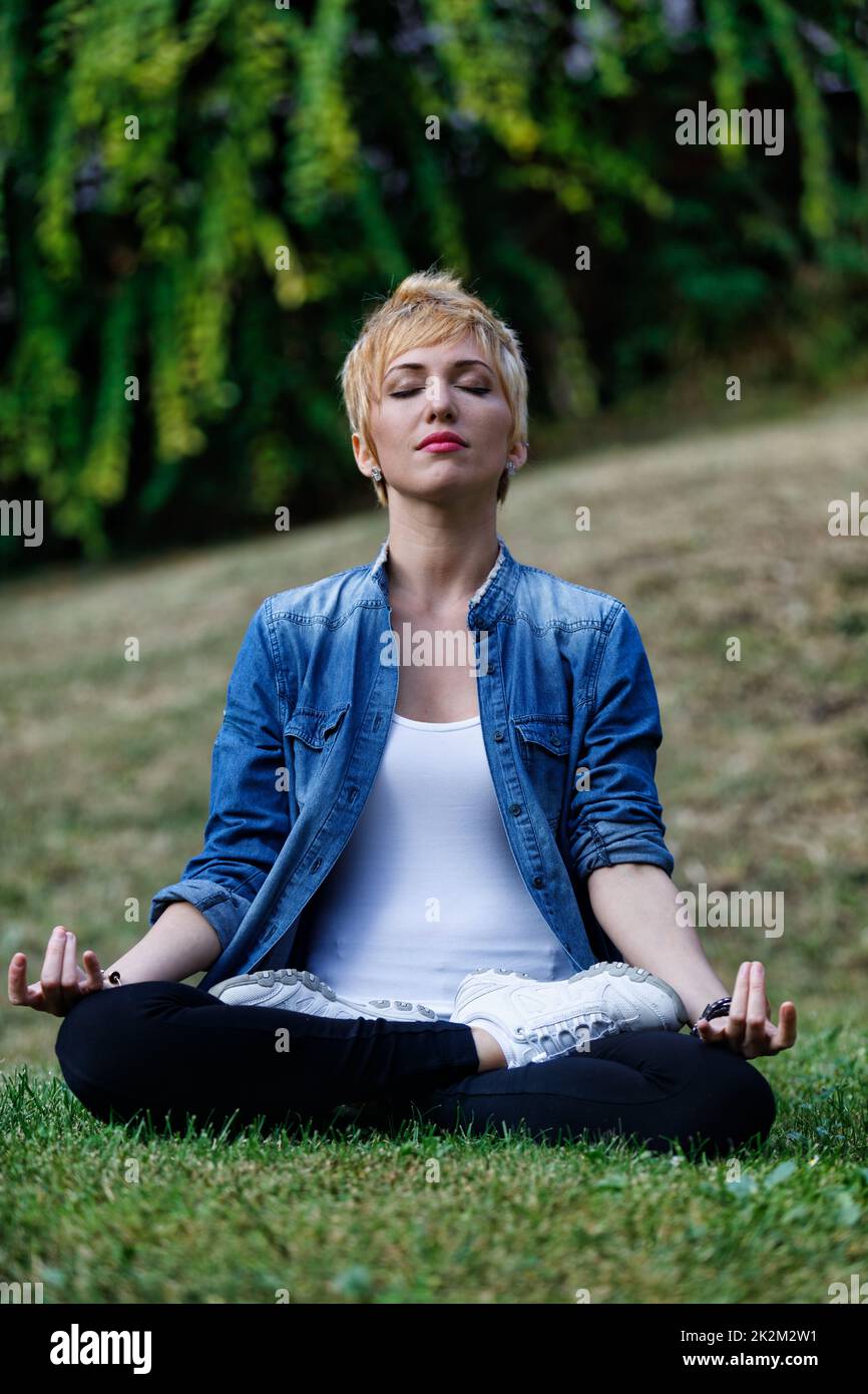Woman in a park meditating hi-res stock photography and images - Alamy