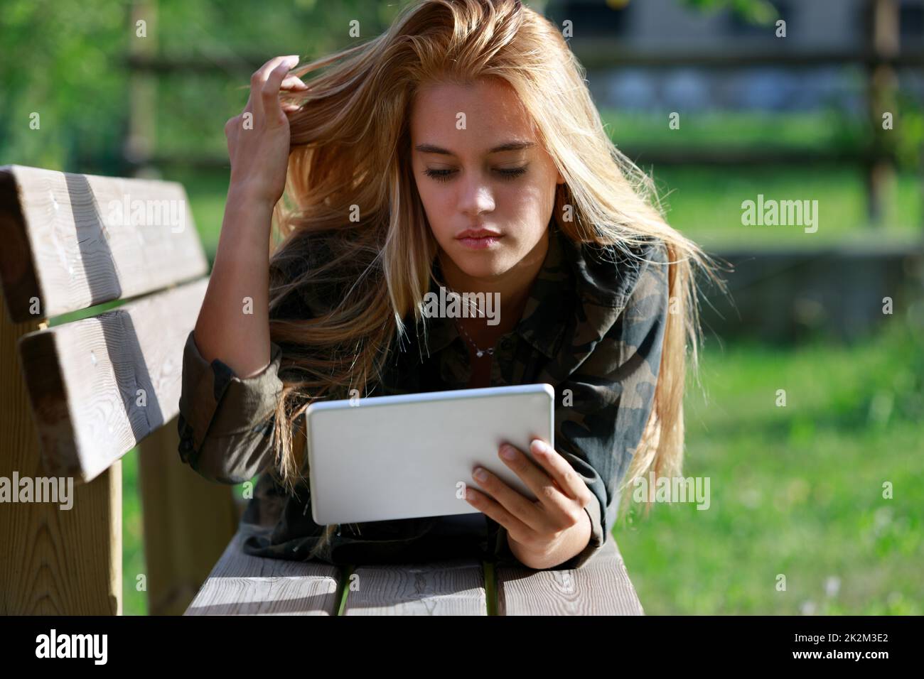 Young woman twiddling with her hair as she relaxes outdoors Stock Photo