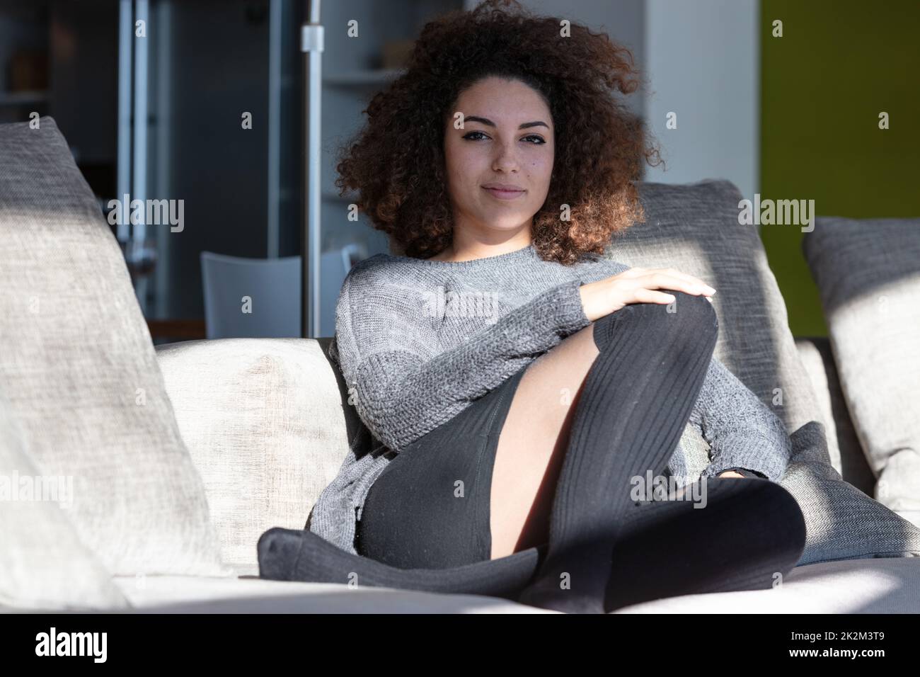 Happy woman sitting in the sun on indoor lounge Stock Photo