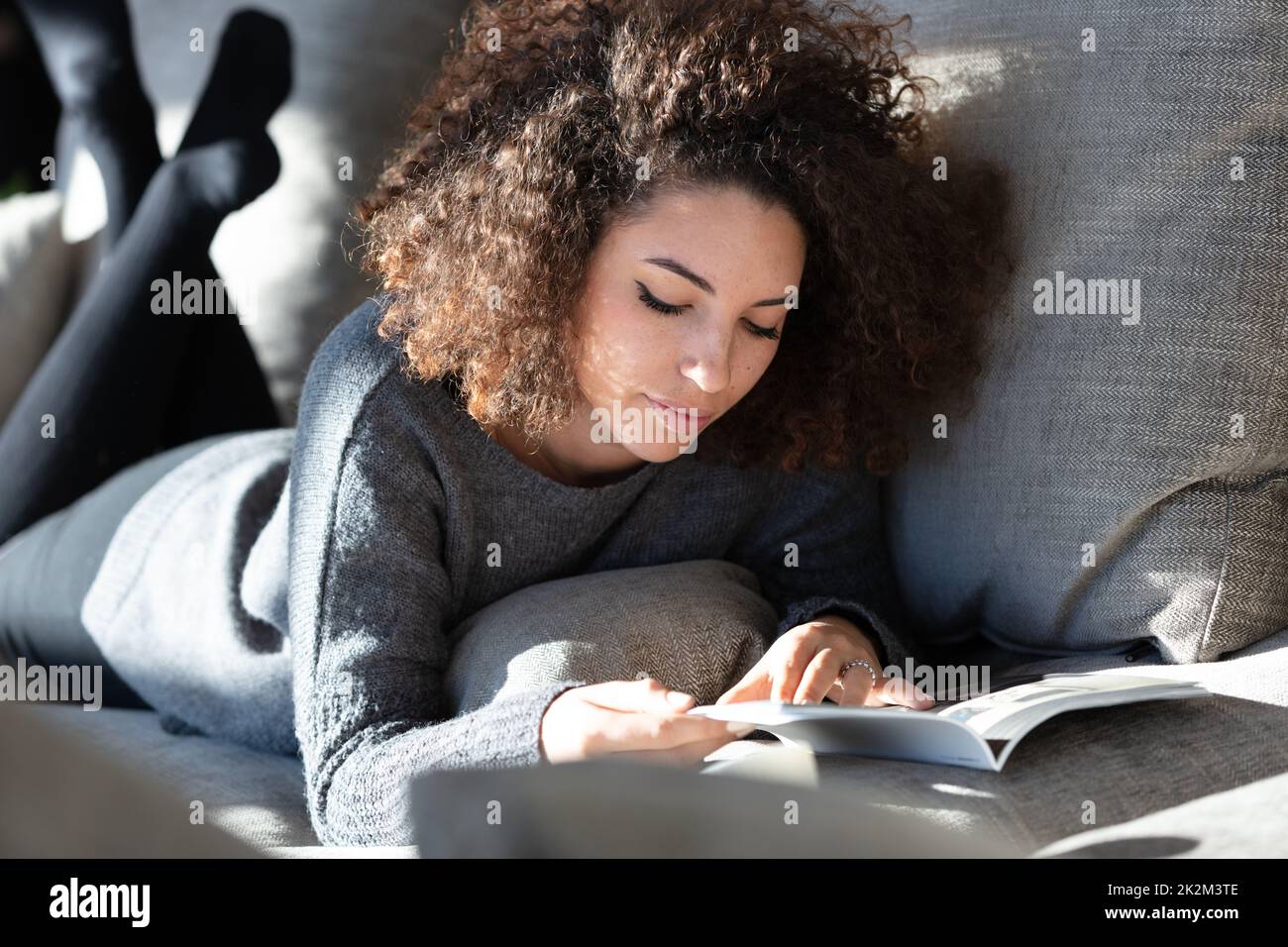 Young woman lying on lounge reading magazine Stock Photo