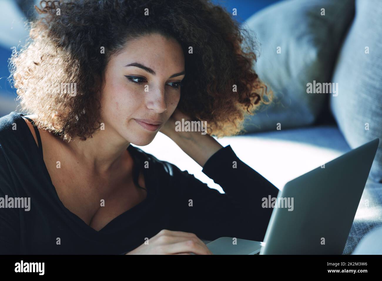 Attractive young woman engrossed in using a laptop computer Stock Photo