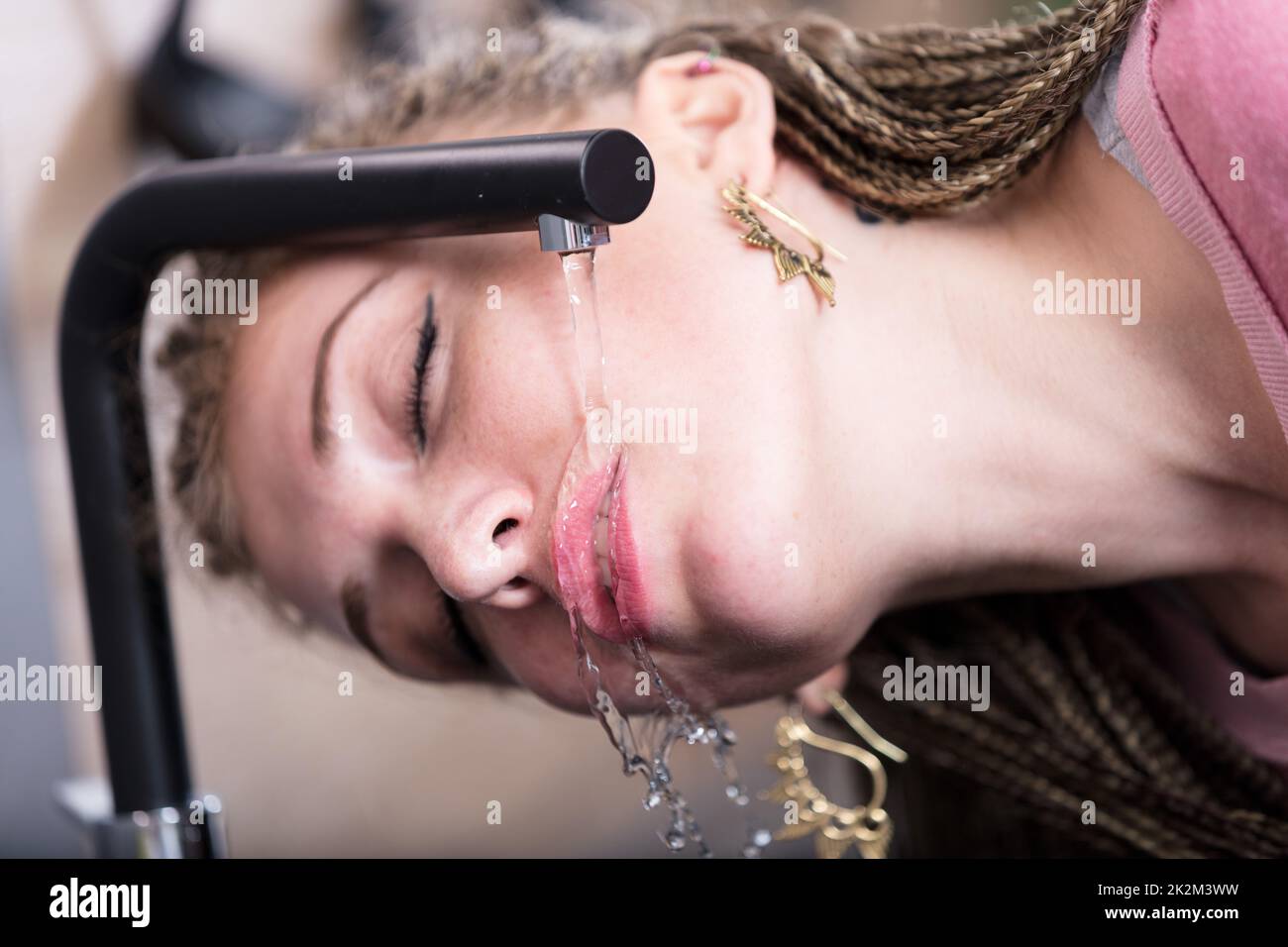 Attractive woman drinking water from a tap Stock Photo