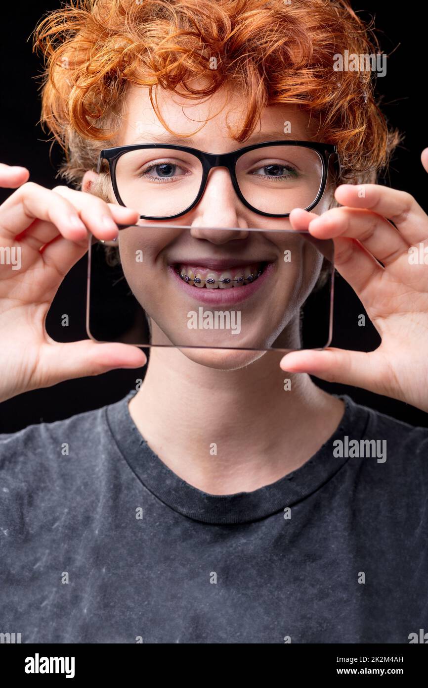 smile of a girl in braces through a transparent mobile phone Stock Photo