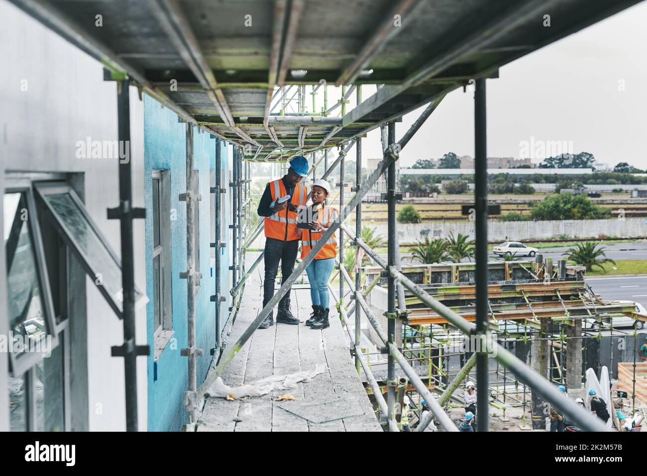 Having organised, digital processes helps keep your project on time. Shot of a young man and woman using a digital tablet while working at a construction site. Stock Photo