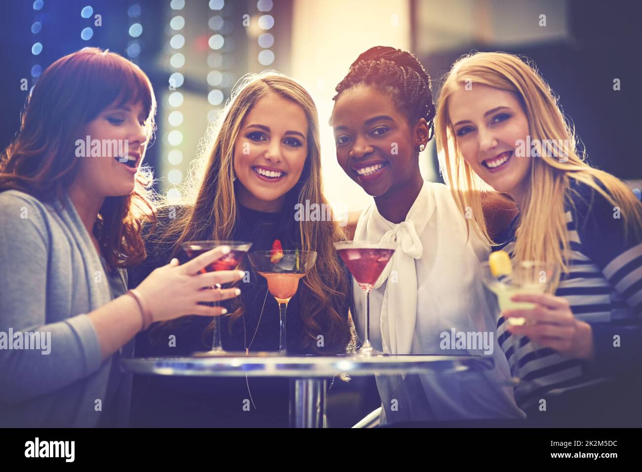 All you need are good friends and fruity drinks. Portrait of a group of happy friends enjoying cocktails in a nightclub. Stock Photo