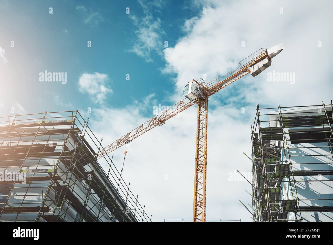 Is it a bird Is it a plane No, its a crane. Shot of a crane and building at a construction site. Stock Photo