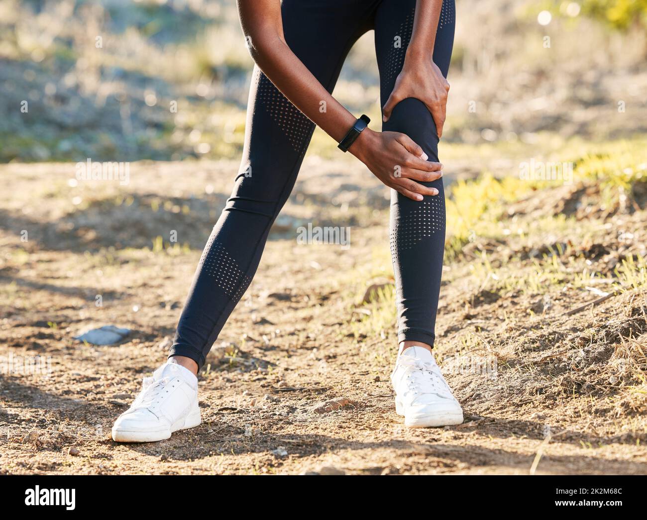 Stretch past the pain. Shot of a woman experiencing knee pain while working out in nature. Stock Photo