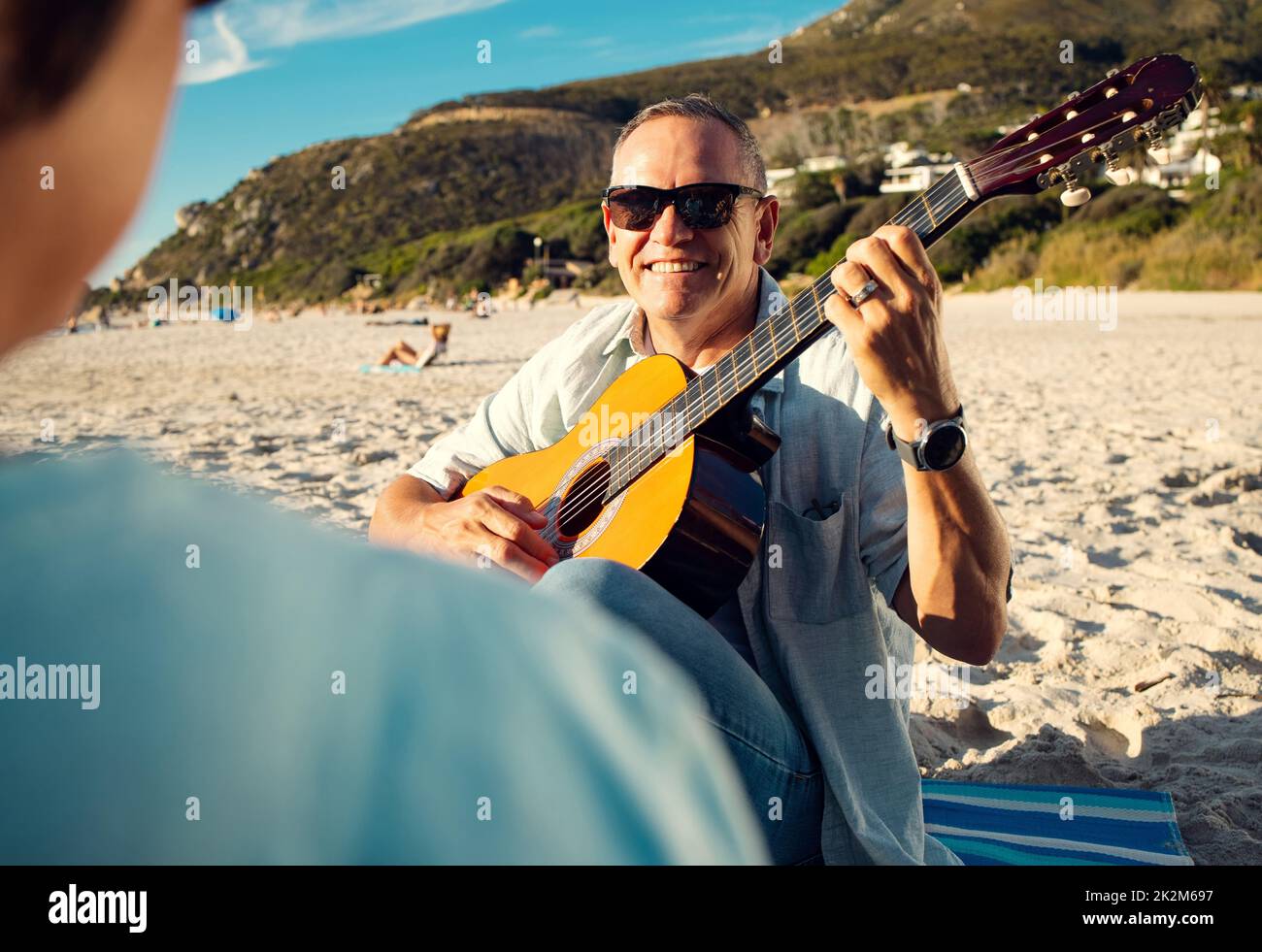 I wrote this song specially for you. Shot of a man playing the guitar while at the beach with his wife. Stock Photo