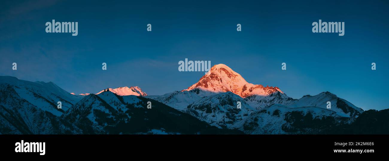 Georgia. Mount Kazbek Covered Snow In Winter Sunrise. Morning Dawn Colored Top Of Mountain In Pink-orange Colors. Awesome Winter Georgian Nature Stock Photo