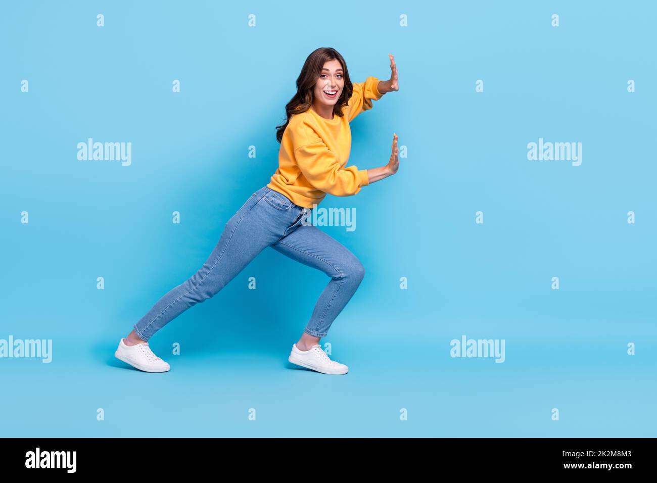 Full length photo of pretty sweet girl dressed yellow pullover pulling huge empty space isolated blue color background Stock Photo