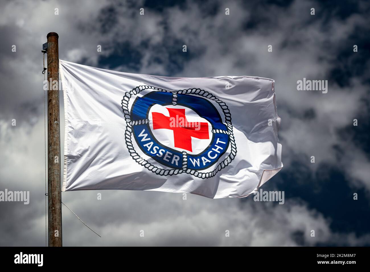Flag of Wasserwacht, part of the German Red Cross, blowing in the wind. Stock Photo