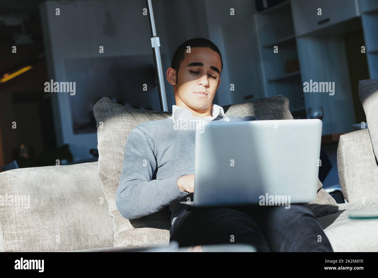 Black man working on his laptop on a comfortable sofa at home Stock Photo