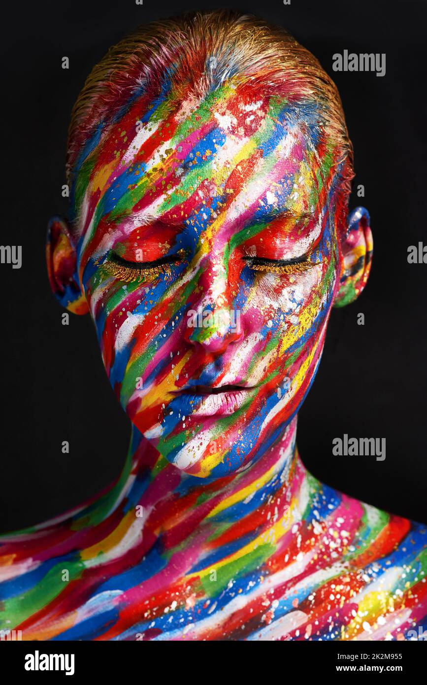 Beauty embraces every color. Studio shot of a young woman posing with brightly colored paint on her face against a black background. Stock Photo