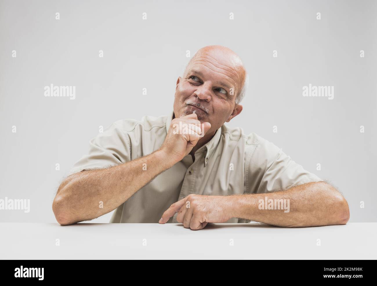 Pleased man sitting thinking with a smile Stock Photo