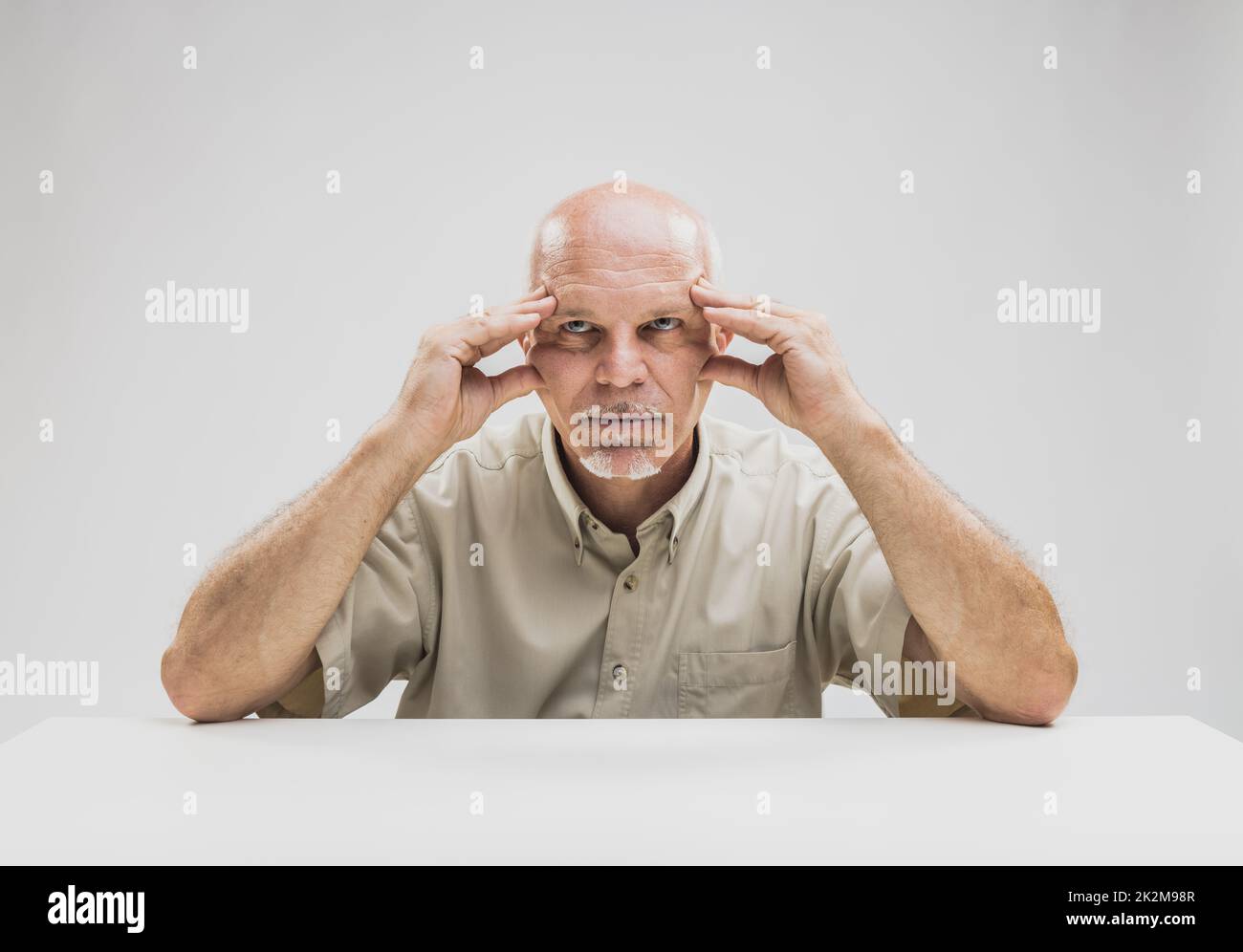 Contemplative balding man sitting at table Stock Photo