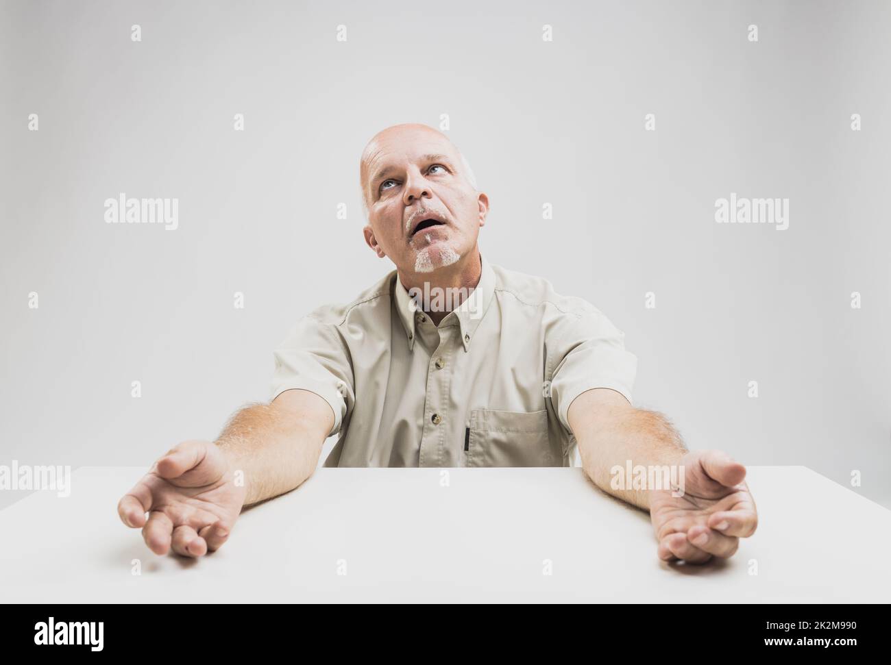 Stressed senior man looking up imploringly Stock Photo