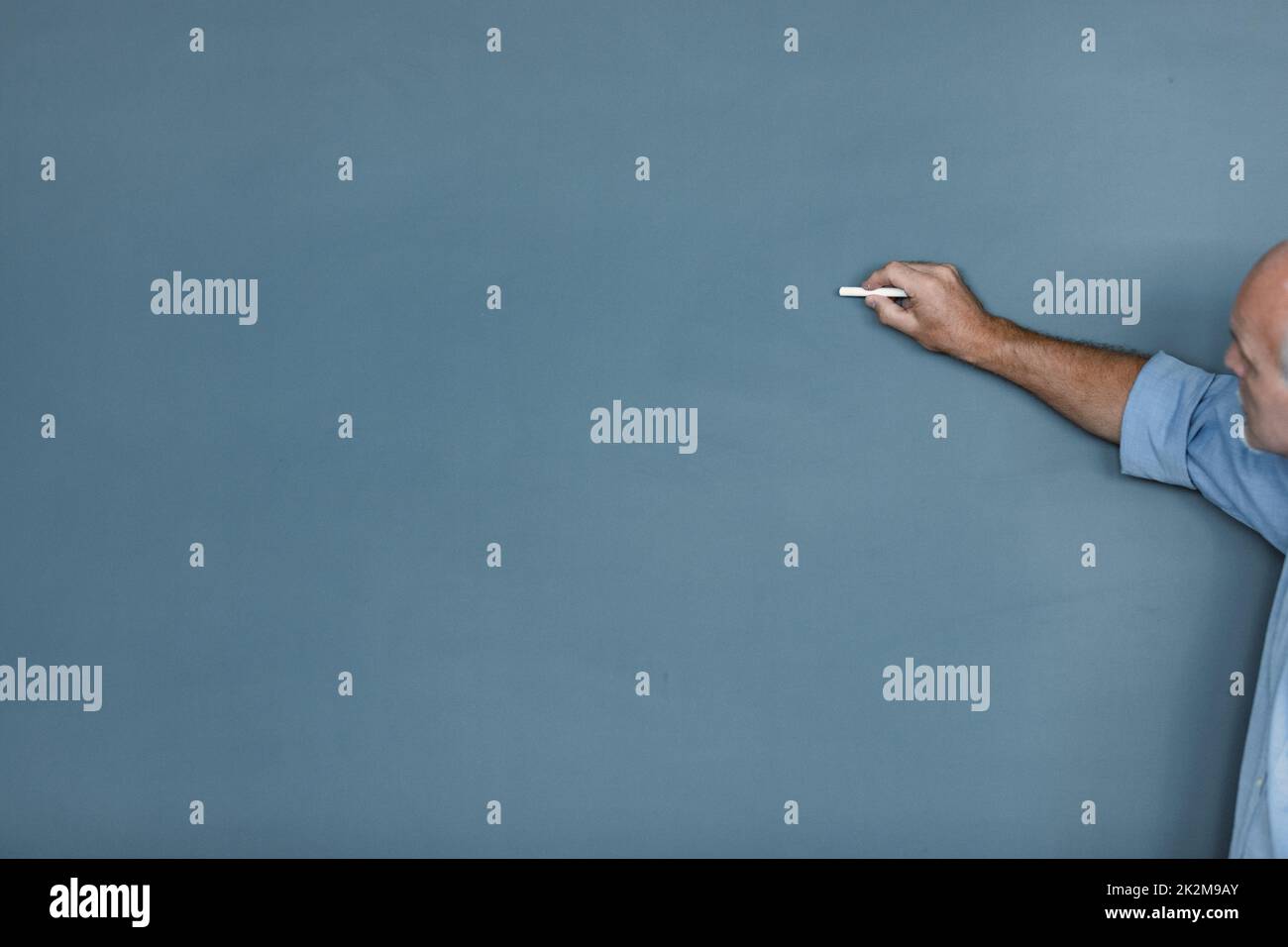 Senior teacher or businessman writing on a blank chalkboard Stock Photo