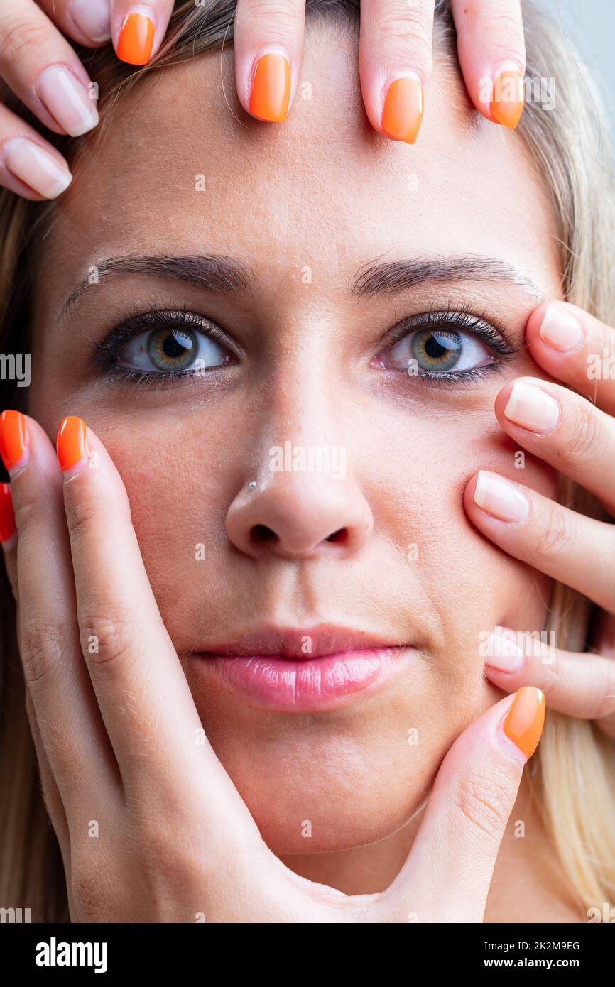 Woman with female hands caressing her face Stock Photo