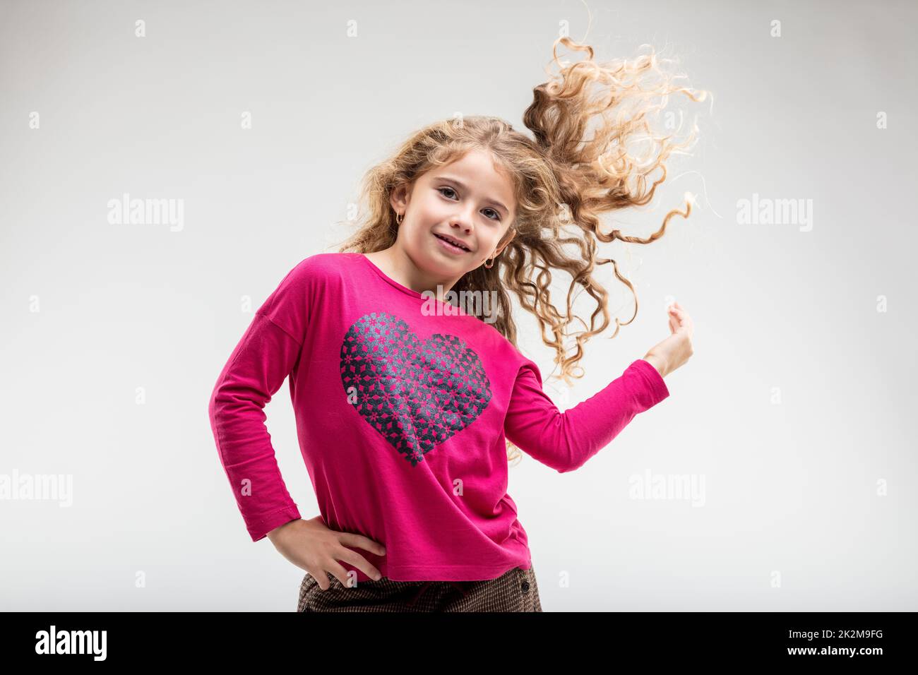 Cheerful preteen girl playing with her curly hair Stock Photo