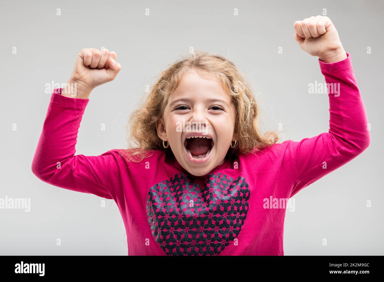 Laughing young schoolgirl raising hands Stock Photo