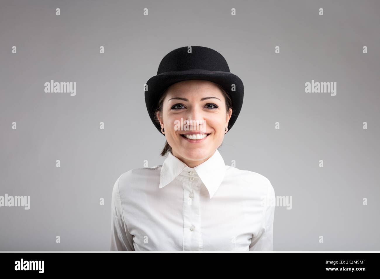 smiling woman in bowler on a gray background Stock Photo