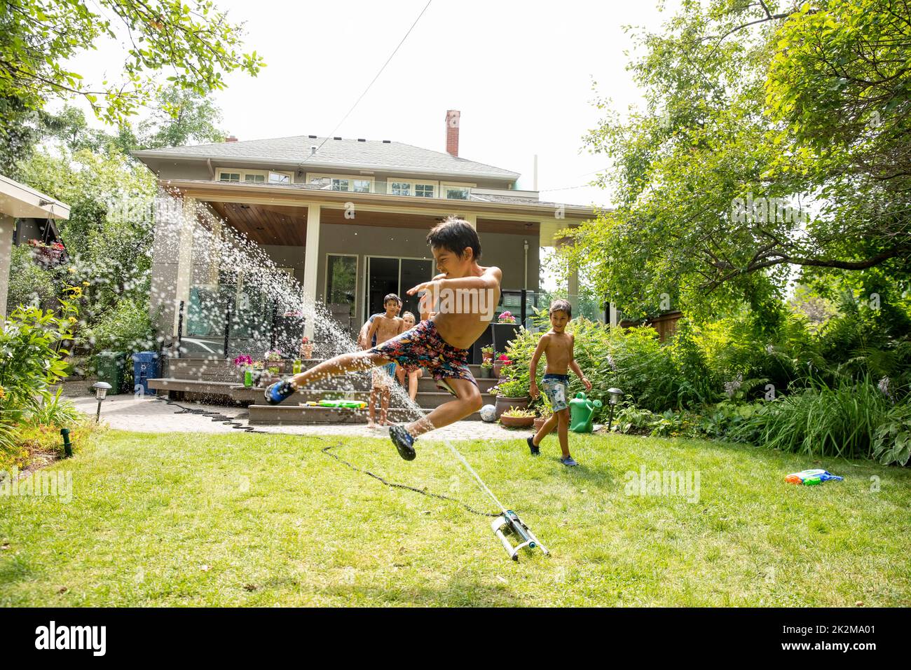 Boy jumping in splashing water in backyard Stock Photo Alamy