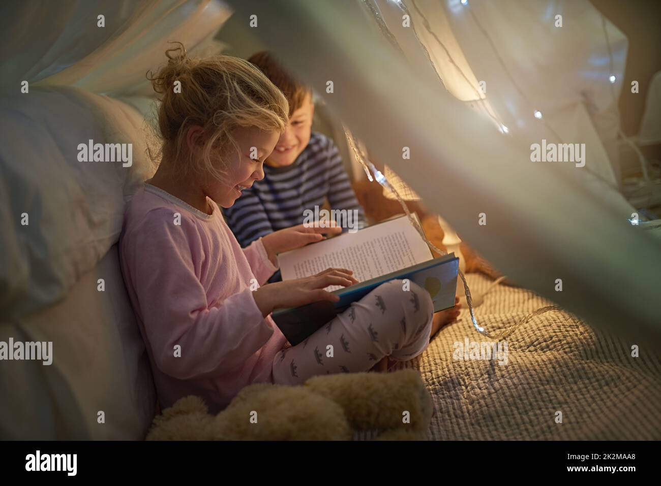 Lets read another one before bedtime. Cropped shot of siblings reading a story under a blanket