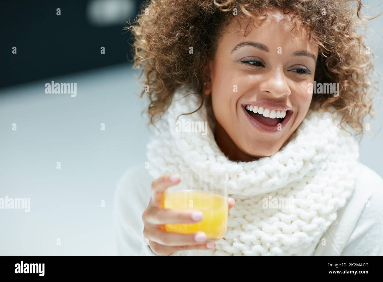 Keeping winter colds and flu at bay the citrusy way. Shot of a young woman dressed in warm clothing drinking a glass of orange juice. Stock Photo