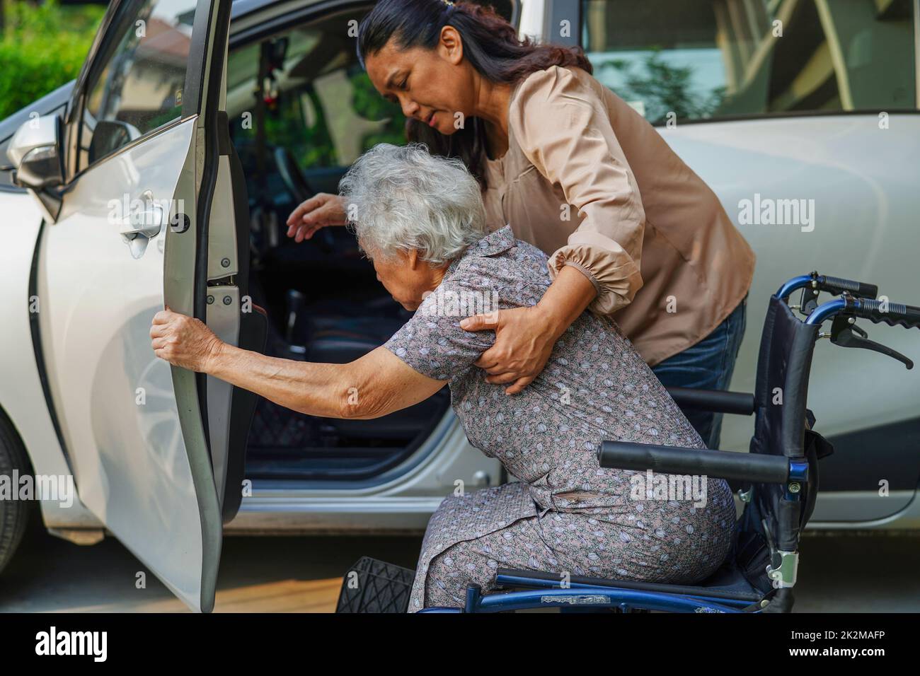 Caregiver help Asian elderly woman disability patient get in her car