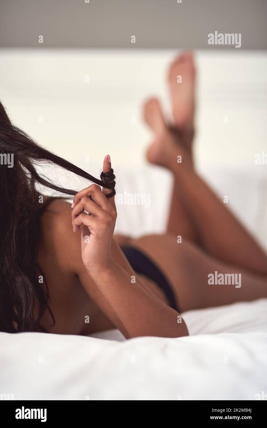 Beautiful in all the right places. Cropped shot of a beautiful naked woman lying on her bed playing with her hair. Stock Photo