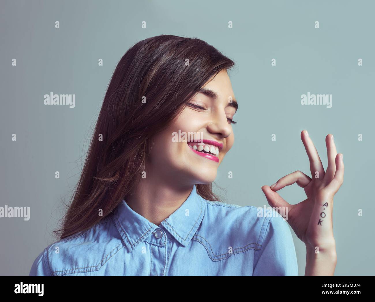 Everything is a-okay. Studio shot of an attractive young woman making an a-okay sign with her hand against a grey background. Stock Photo