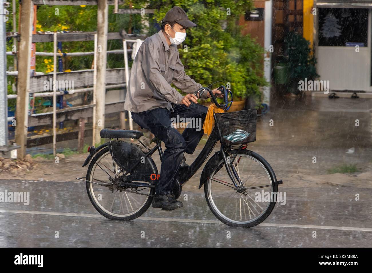 SAMUT PRAKAN, THAILAND, SEP 21 2022, A man rides a bicycle on the street in heavy rain Stock Photo