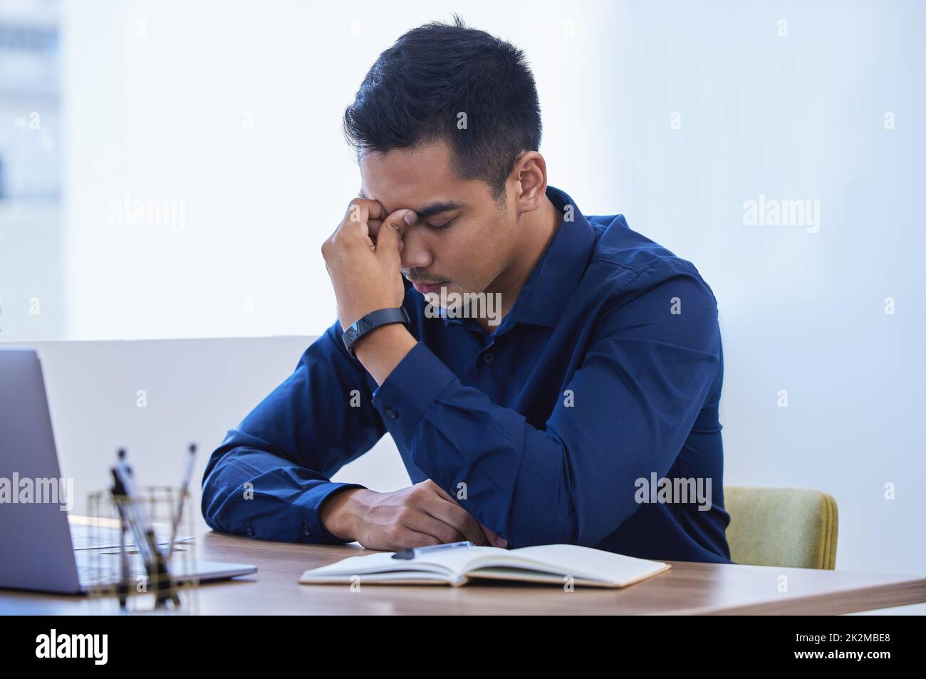 Overwhelmed with too much to do. Shot of a young businessman looking stressed out while working in an office. Stock Photo