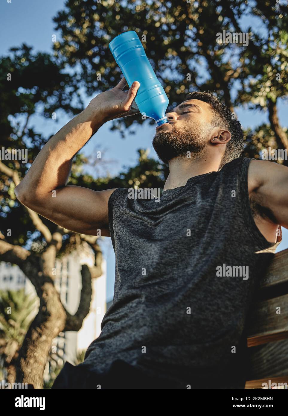 That was quite a workout. Low angle shot of a sporty young man drinking water while exercising outdoors. Stock Photo
