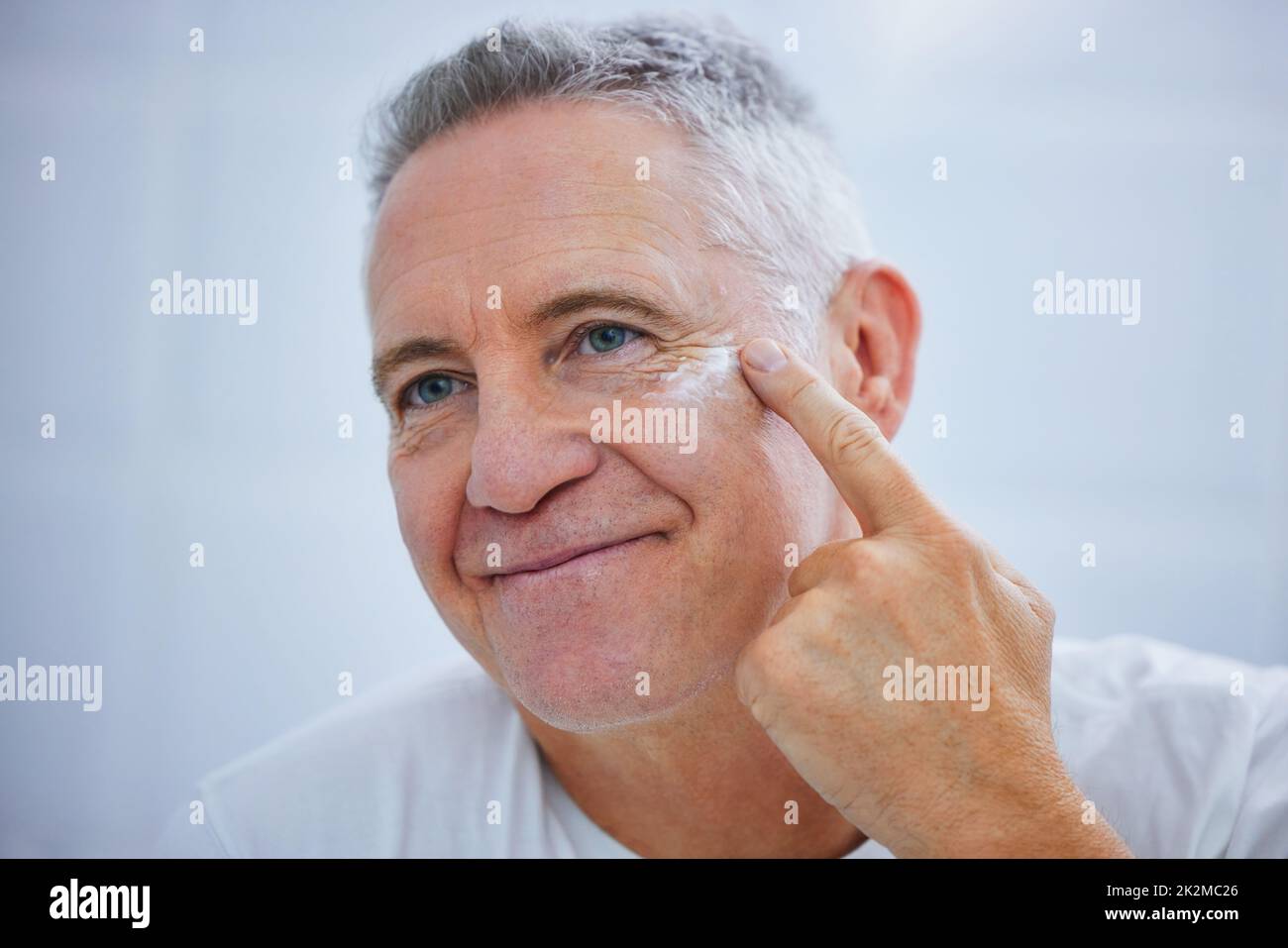 Cant forget to moisturise. Shot of a mature man applying cream to his face in a bathroom at home. Stock Photo