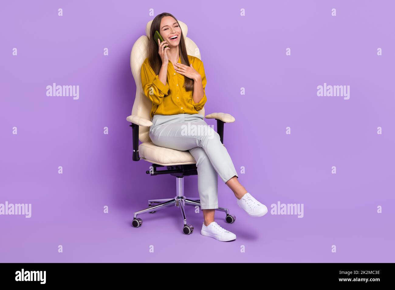 Full size photo of lady sit talk telephone wear blouse trousers sneakers isolated on purple color background Stock Photo