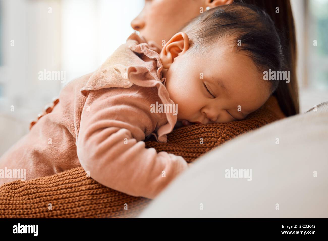 This little one loves nap time. Shot of an adorable baby girl sleeping on her mothers arms. Stock Photo