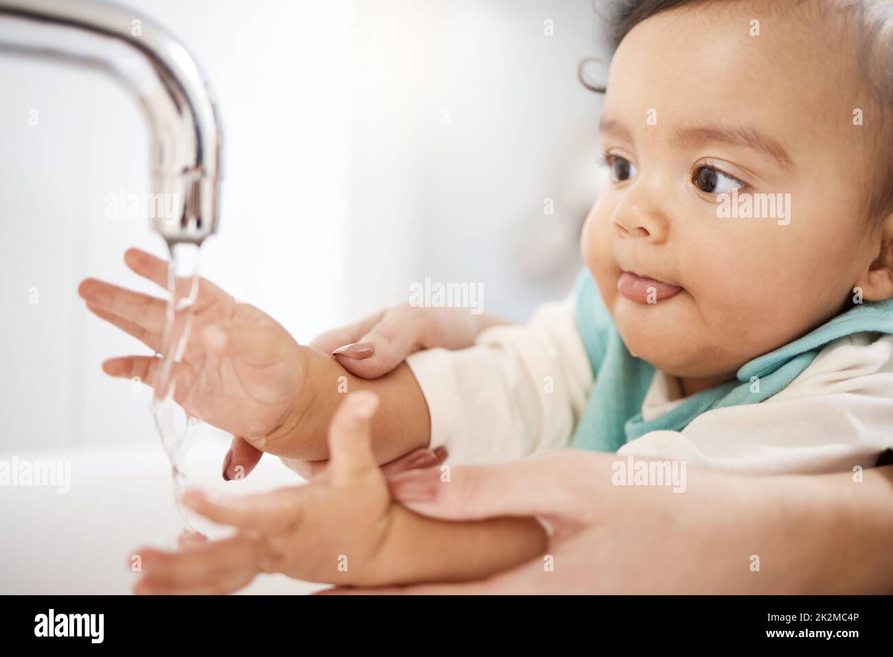 Id much rather drink it. Cropped shot of a woman washing her babys hands. Stock Photo