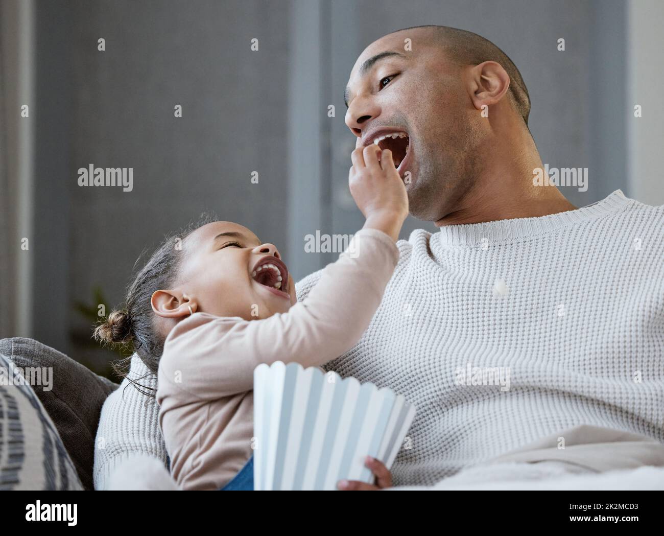 Shot of a father and daughter eating popcorn while watching television
