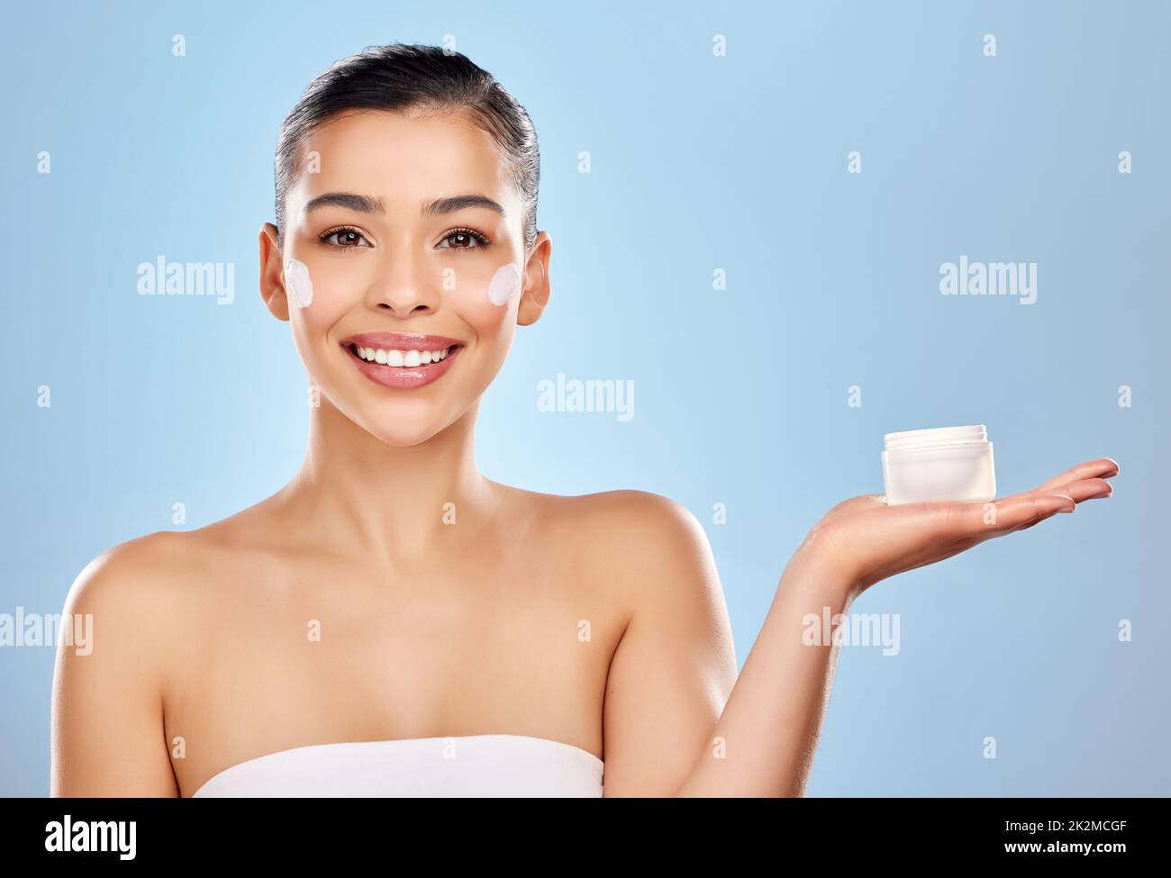 You wont find anything better than this for your skin. Studio portrait of an attractive young woman holding a beauty product against a blue background. Stock Photo
