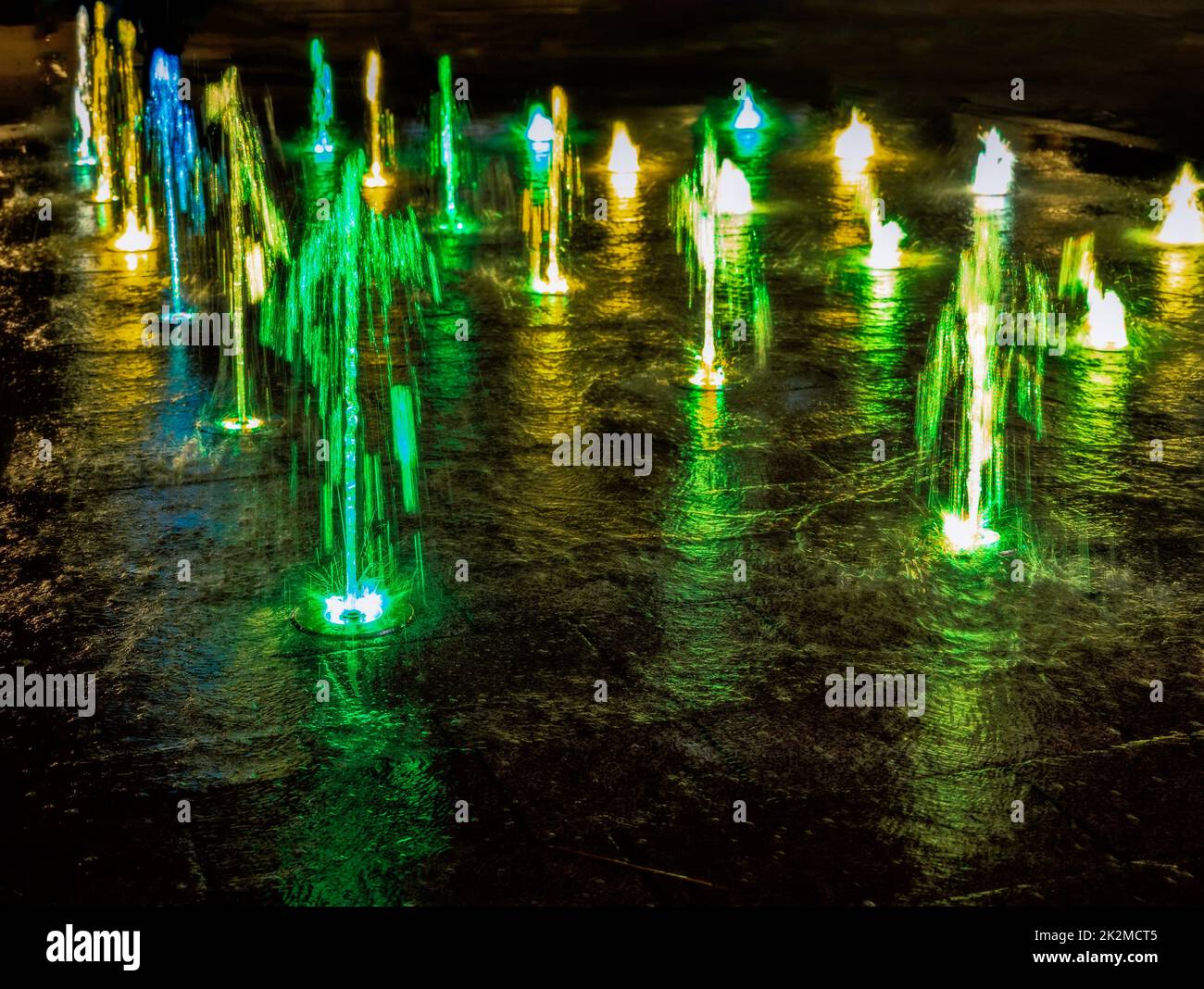 Illuminated waterspout fountain at night Stock Photo