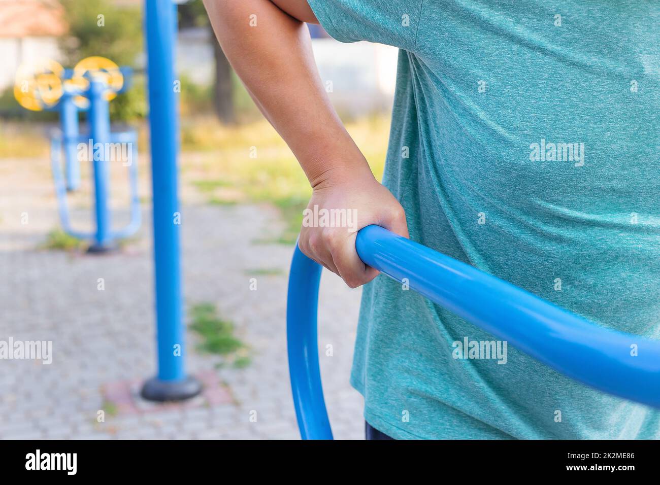 A man is exercising on the street. Training for beautiful hands. Opening gym outdoors on the sports ground in a green park. Stock Photo