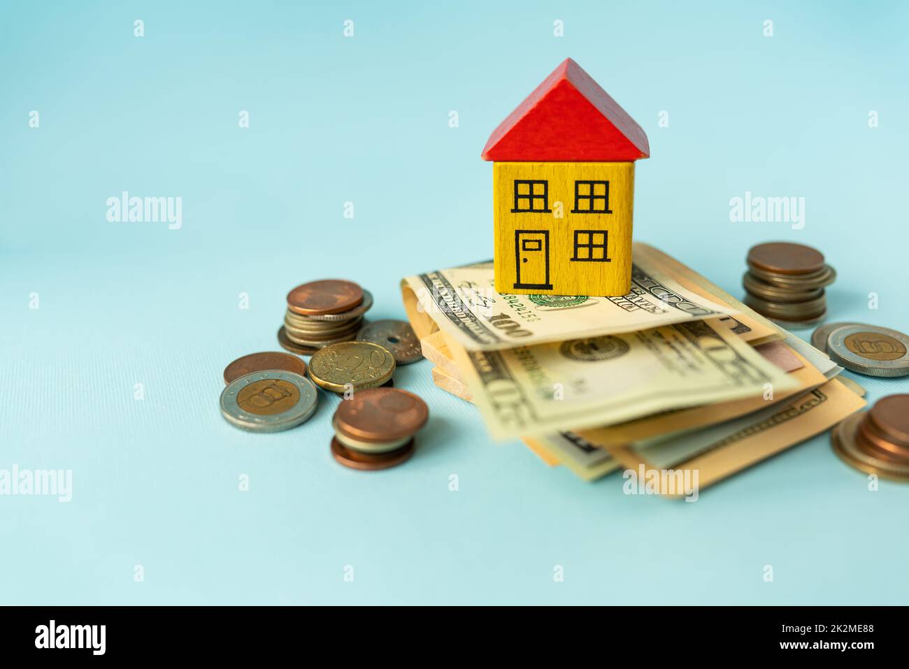Money in international currency, including euro, dollar, a coin on which there is a toy house. The concept of mortgages, investments, loans, debts, housing purchases: apartments or houses. Stock Photo