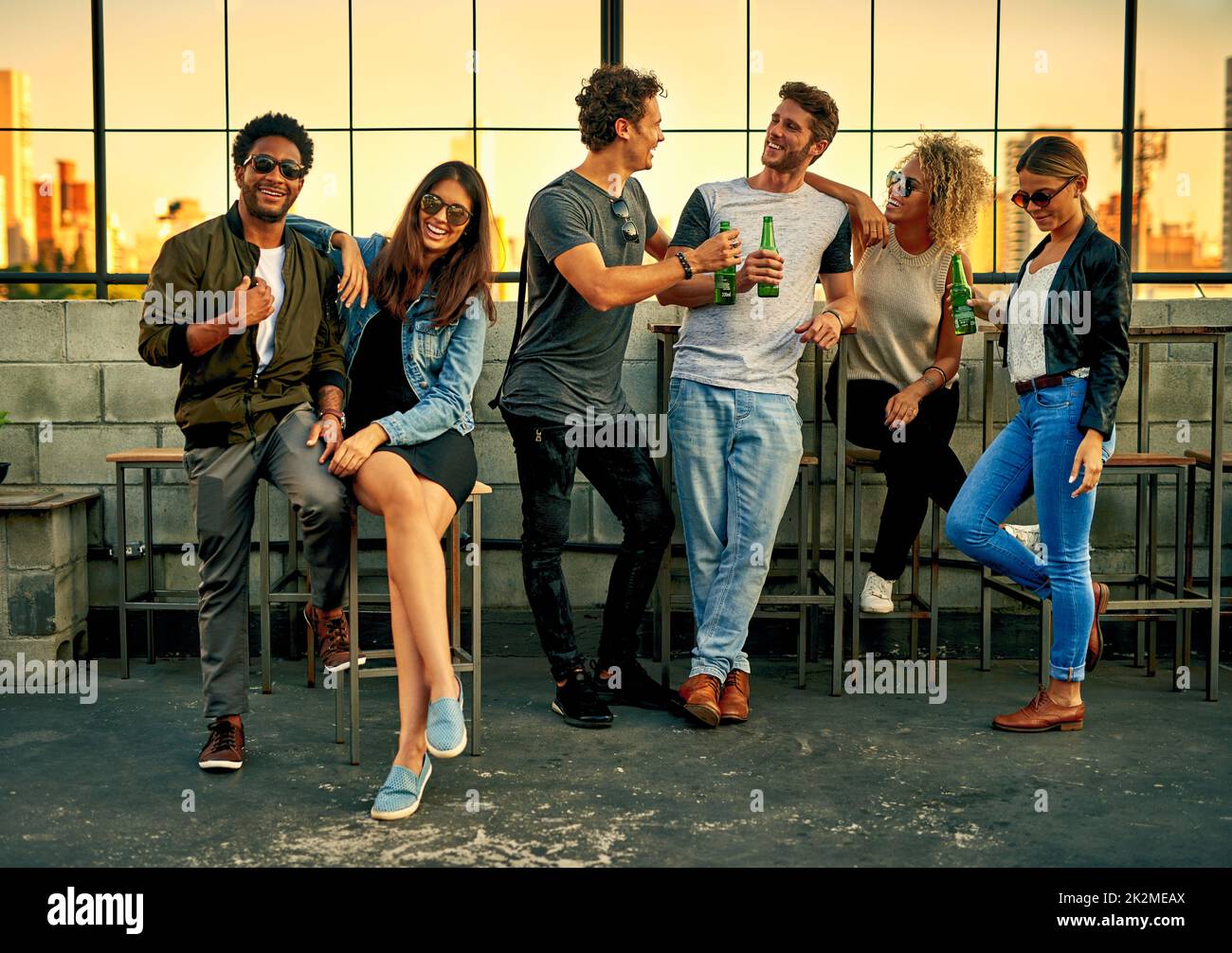 Get together and let the good times roll. Shot of a group of young friends hanging out and having drinks together outdoors. Stock Photo