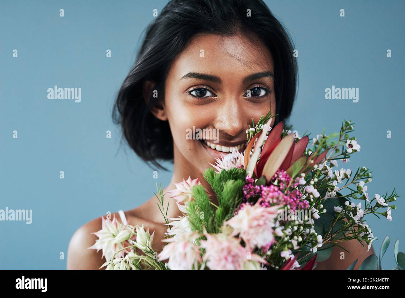 Flowers are a surefire way to grab a womans attention. Cropped shot of a beautiful young woman posing with a bouquet of flowers. Stock Photo