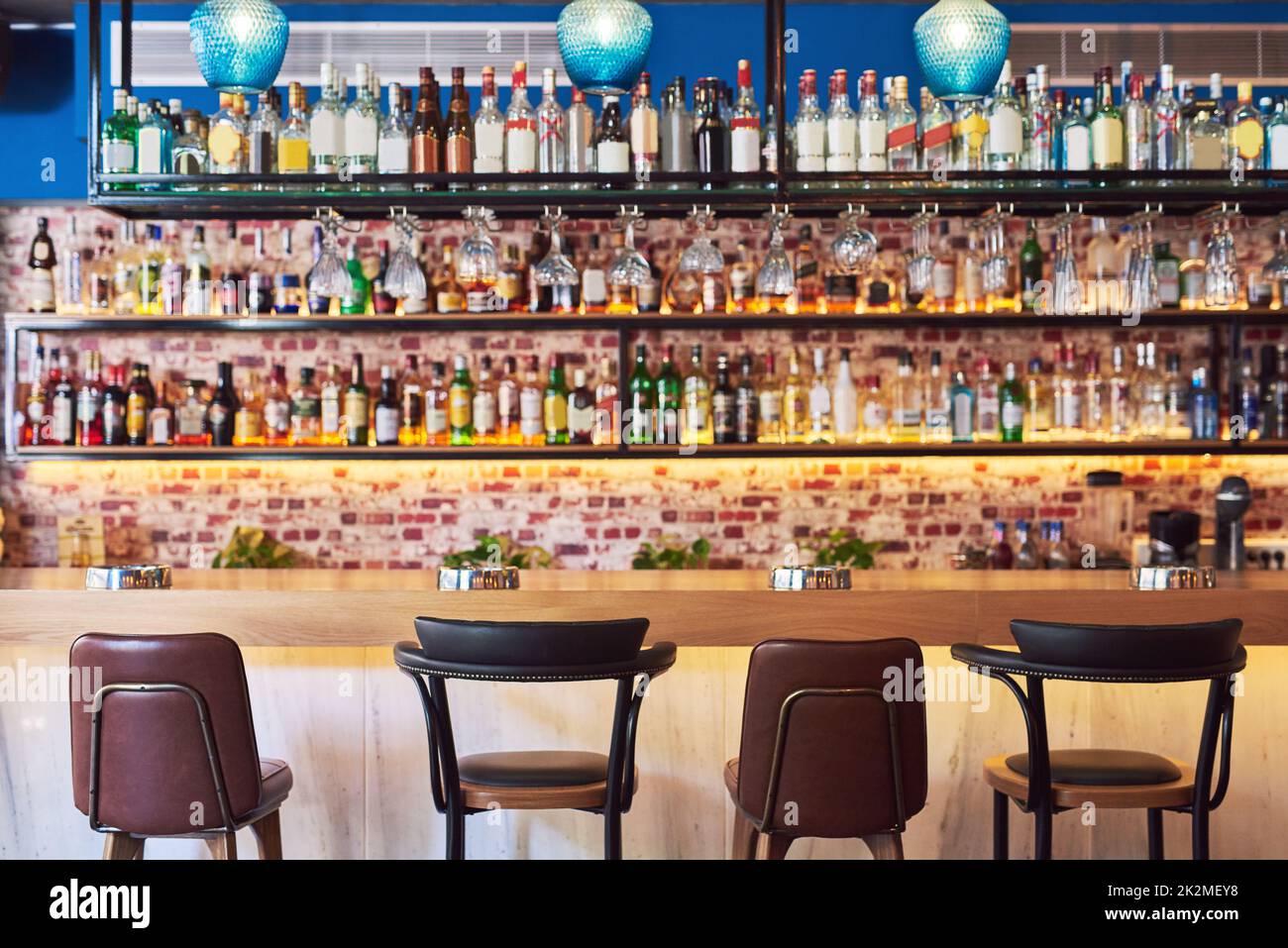 The place to go to have fun. Shot of an immaculate bar with many bottles and glasses with no people. Stock Photo